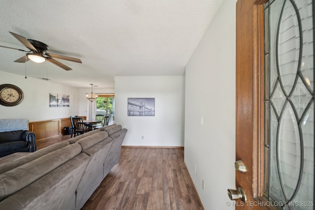 living area with ceiling fan, dark wood-style flooring, baseboards, a chandelier, and a textured ceiling