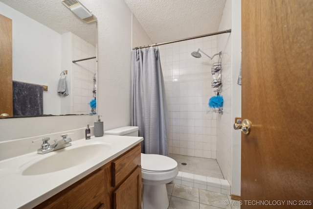 bathroom featuring toilet, tiled shower, vanity, a textured ceiling, and tile patterned flooring