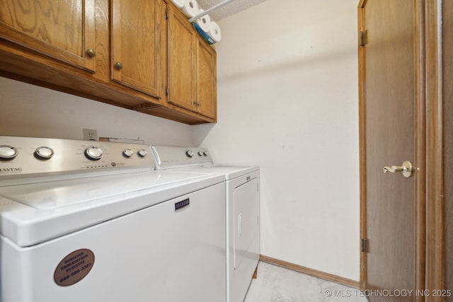 washroom featuring washer and dryer, cabinet space, and baseboards
