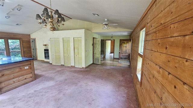 kitchen with lofted ceiling, a chandelier, wooden walls, carpet, and a ceiling fan