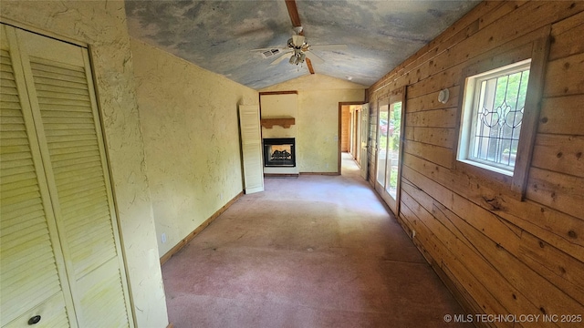 hallway featuring vaulted ceiling and wooden walls