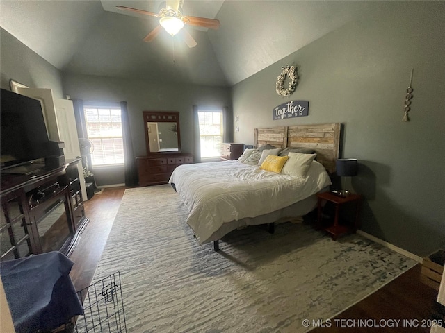 bedroom with lofted ceiling, wood finished floors, baseboards, a wood stove, and ceiling fan