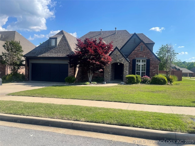 view of front of property featuring driveway, an attached garage, a front yard, and a shingled roof