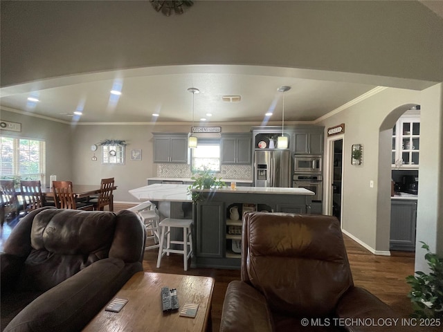 living area featuring dark wood finished floors, crown molding, arched walkways, recessed lighting, and baseboards
