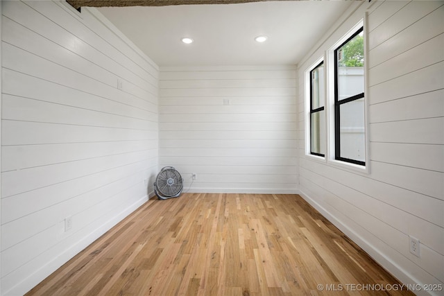 spare room with wood-type flooring, wood walls, recessed lighting, and baseboards