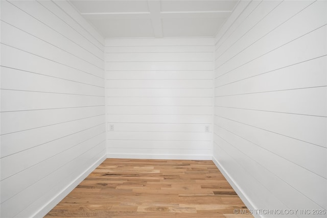 spare room with light wood-type flooring, wood walls, and baseboards