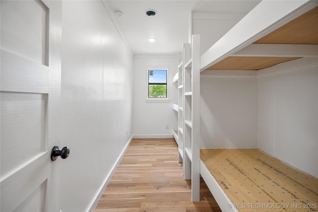 corridor featuring light wood finished floors, baseboards, crown molding, and recessed lighting