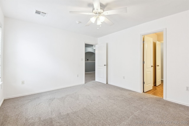 unfurnished bedroom featuring carpet flooring, baseboards, ensuite bathroom, and a ceiling fan