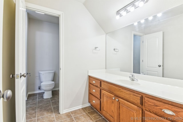 bathroom with toilet, vanity, baseboards, and lofted ceiling