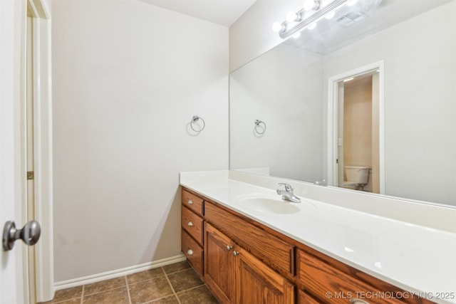 bathroom featuring toilet, vanity, baseboards, and tile patterned floors