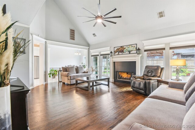living room featuring high vaulted ceiling, plenty of natural light, a tiled fireplace, ceiling fan, and dark wood-style flooring