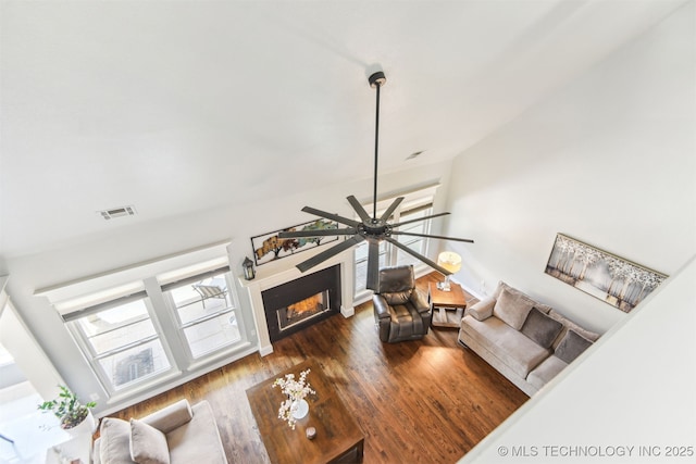 living room with a lit fireplace, a ceiling fan, wood finished floors, and vaulted ceiling
