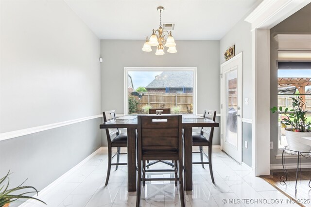 dining room with a chandelier, light marble finish flooring, and baseboards