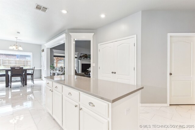 kitchen with light marble finish floors, a chandelier, a kitchen island, white cabinets, and recessed lighting