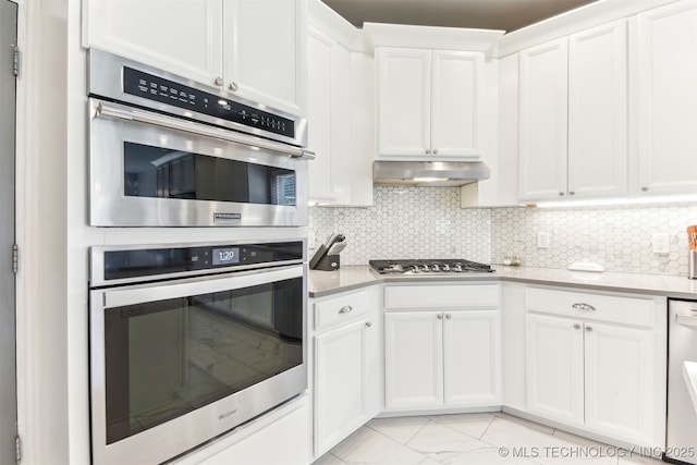 3909 W Utica St, Broken Arrow, OK 74011 - kitchen featuring stainless steel appliances, light countertops, white cabinetry, under cabinet range hood, and decorative backsplash