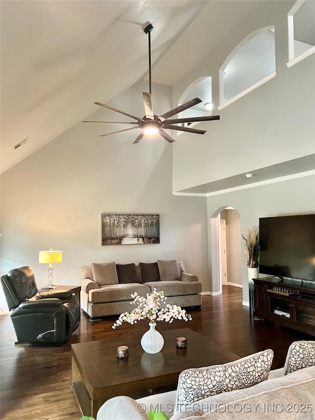 living room featuring arched walkways, high vaulted ceiling, a ceiling fan, wood finished floors, and baseboards