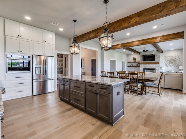 3241 E 171st St S, Bixby, OK 74008 - kitchen with appliances with stainless steel finishes, light wood-style flooring, beamed ceiling, a stone fireplace, and white cabinets