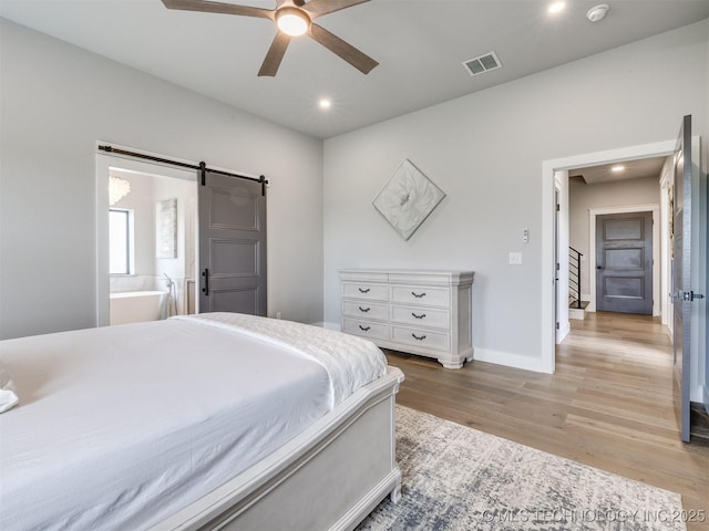 3241 E 171st St S, Bixby, OK 74008 - bedroom with wood finished floors, recessed lighting, a barn door, baseboards, and connected bathroom