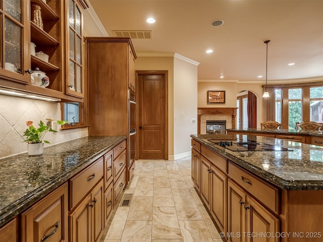 kitchen with black electric stovetop, crown molding, brown cabinets, baseboards, and pendant lighting