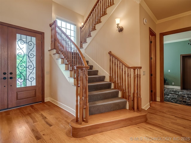 entryway featuring stairs, wood finished floors, baseboards, and crown molding