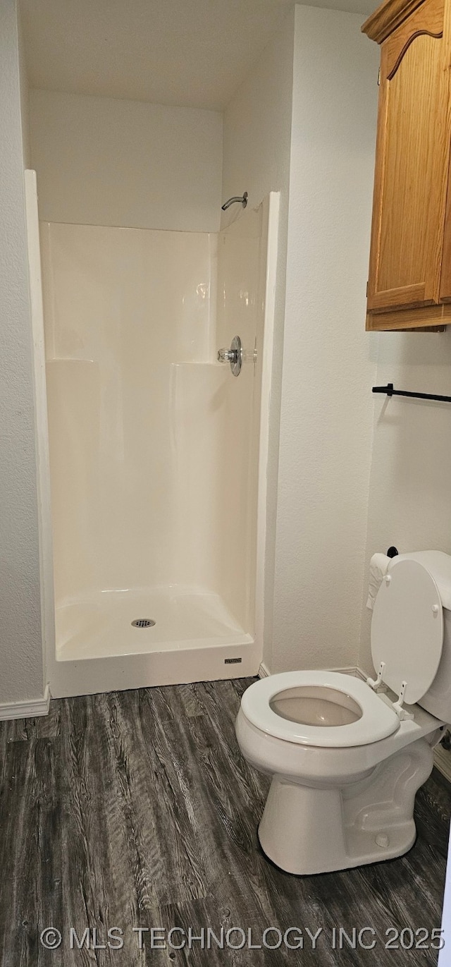 103 E Iola, Sallisaw, OK 74955 - bathroom with toilet, a stall shower, and wood finished floors