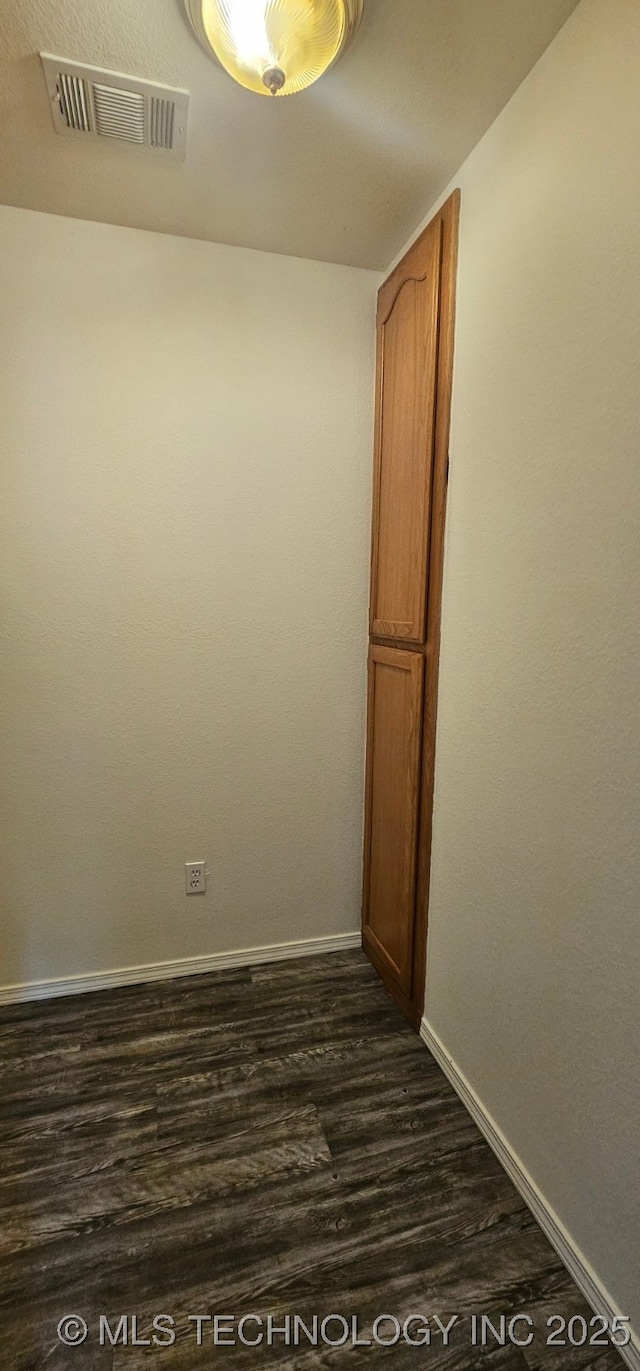 103 E Iola, Sallisaw, OK 74955 - spare room featuring baseboards and dark wood-style flooring