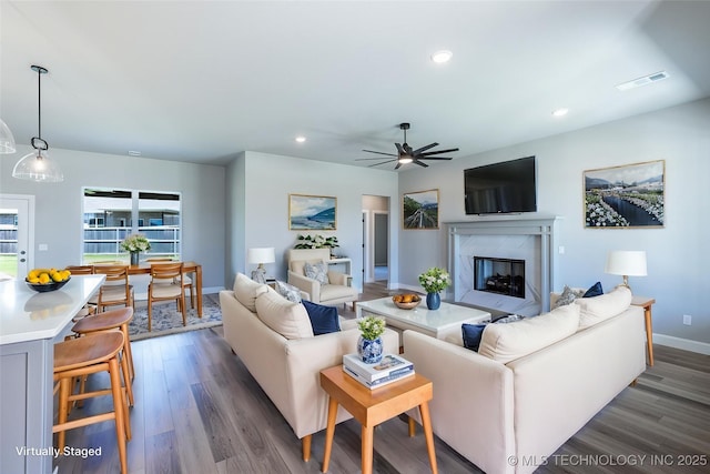 living area with wood finished floors, a ceiling fan, recessed lighting, a premium fireplace, and baseboards