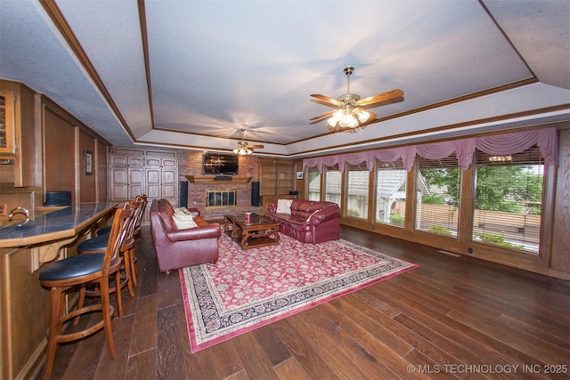 8734 S Richmond Ave, Tulsa, OK 74137 - living area featuring a raised ceiling, a ceiling fan, a brick fireplace, dark wood finished floors, and a textured ceiling