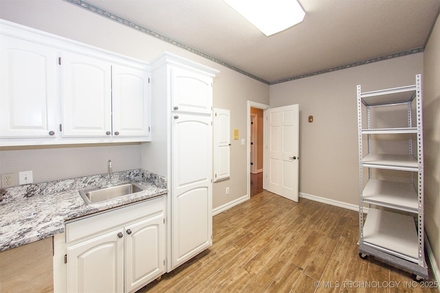 8734 S Richmond Ave, Tulsa, OK 74137 - kitchen featuring a sink, light wood-type flooring, white cabinetry, and baseboards