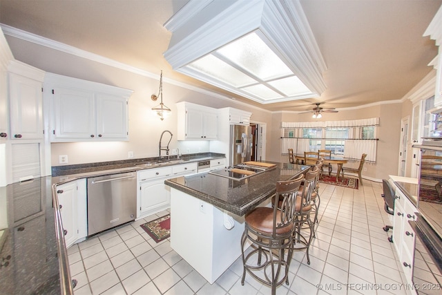8734 S Richmond Ave, Tulsa, OK 74137 - kitchen with appliances with stainless steel finishes, ceiling fan, light tile patterned floors, white cabinets, and a breakfast bar area