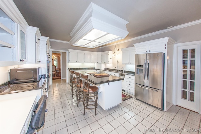 8734 S Richmond Ave, Tulsa, OK 74137 - kitchen with stainless steel fridge, crown molding, dark countertops, a breakfast bar area, and light tile patterned floors