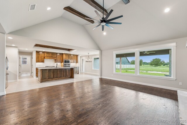 unfurnished living room with a chandelier, high vaulted ceiling, ceiling fan, recessed lighting, and baseboards