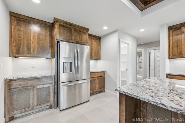 kitchen with stainless steel fridge, light stone countertops, recessed lighting, baseboards, and light tile patterned floors