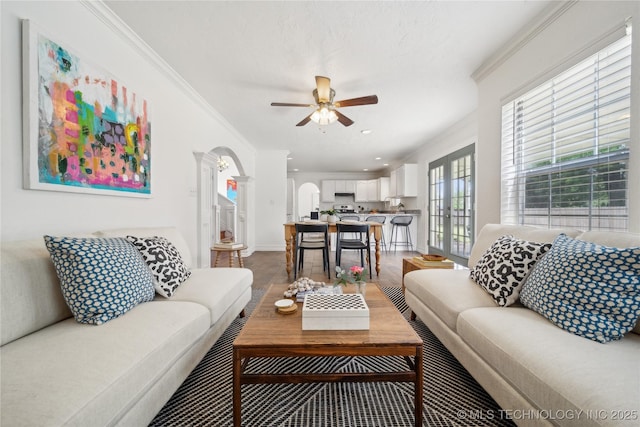 living area with arched walkways, a ceiling fan, wood finished floors, crown molding, and recessed lighting