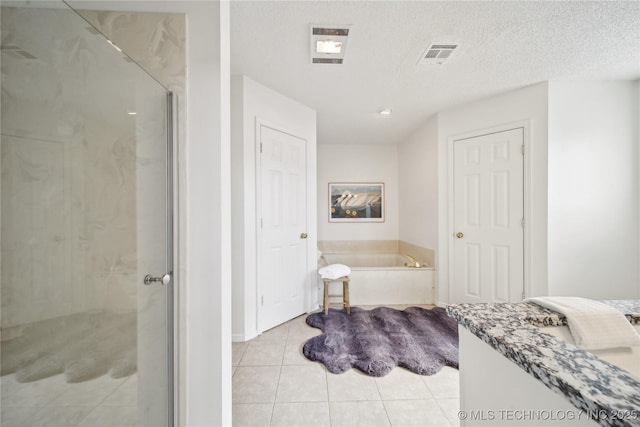 bathroom featuring tile patterned flooring, a shower stall, a bath, baseboards, and a textured ceiling