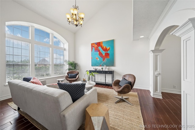living room featuring decorative columns, arched walkways, a chandelier, dark wood finished floors, and baseboards