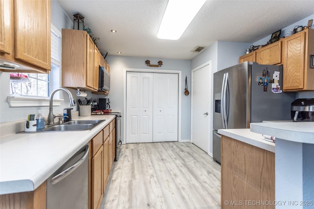 10862 Hide-A-Way, Thackerville, OK 73459 - kitchen with appliances with stainless steel finishes, light countertops, light wood finished floors, a textured ceiling, and a sink