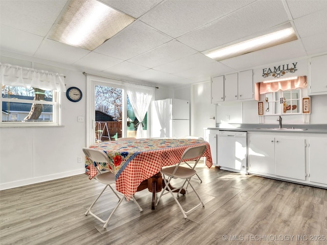 410 W B J Tunnell, Miami, OK 74354 - dining space featuring light wood-style flooring, plenty of natural light, a paneled ceiling, and baseboards
