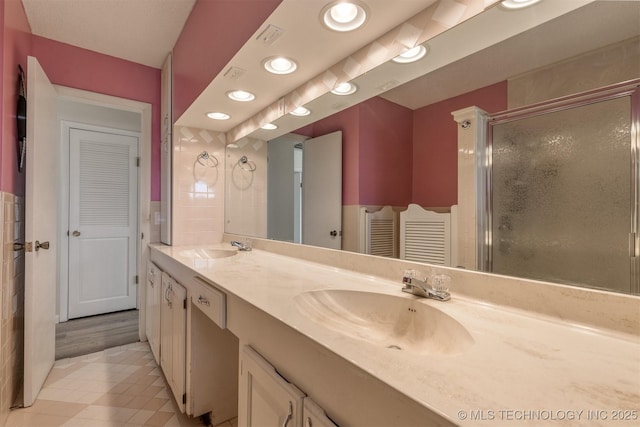 bathroom with double vanity, a stall shower, tile patterned flooring, and recessed lighting