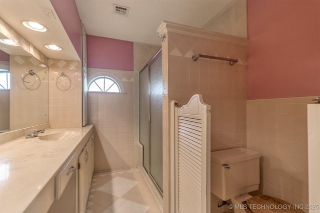 bathroom featuring tile walls, a stall shower, toilet, and vanity