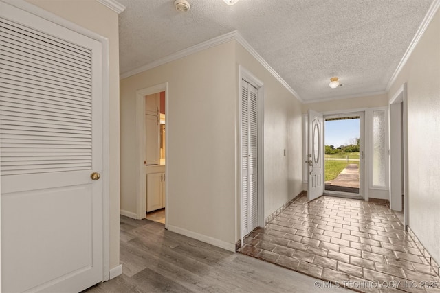 corridor with a textured ceiling, baseboards, and ornamental molding
