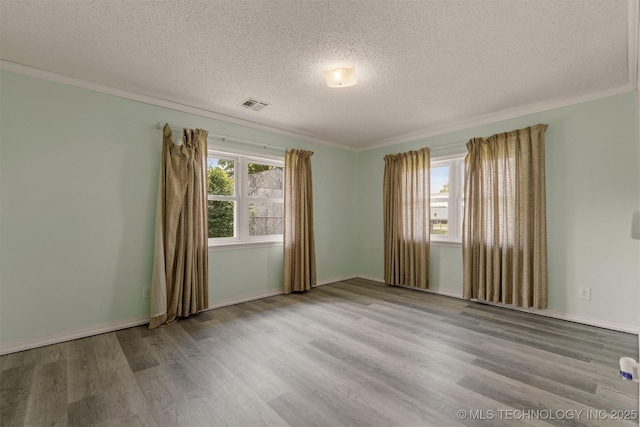 empty room featuring wood finished floors, a textured ceiling, crown molding, and baseboards