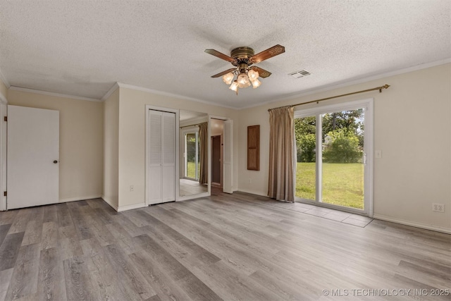 spare room featuring ceiling fan, a textured ceiling, wood finished floors, ornamental molding, and baseboards