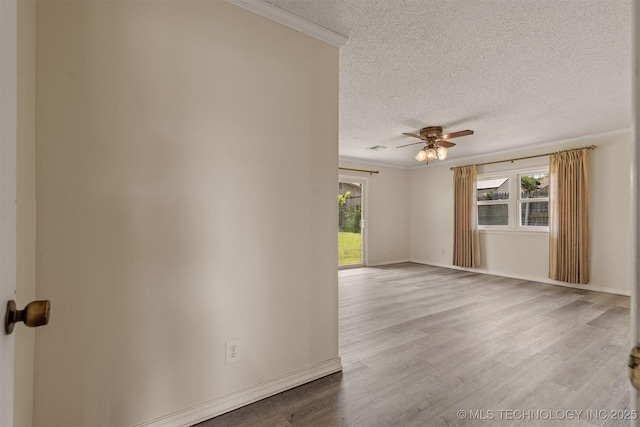 empty room with a textured ceiling, wood finished floors, ceiling fan, ornamental molding, and baseboards
