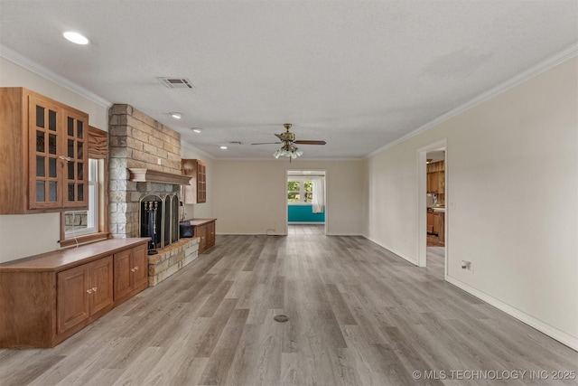 unfurnished living room with ceiling fan, light wood-style floors, crown molding, a fireplace, and baseboards
