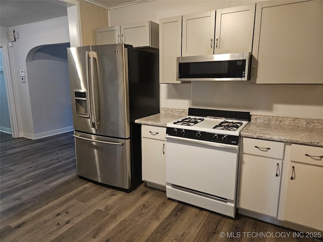 1435 E Oak St, Cushing, OK 74023 - kitchen with appliances with stainless steel finishes, crown molding, dark wood-style flooring, light countertops, and arched walkways