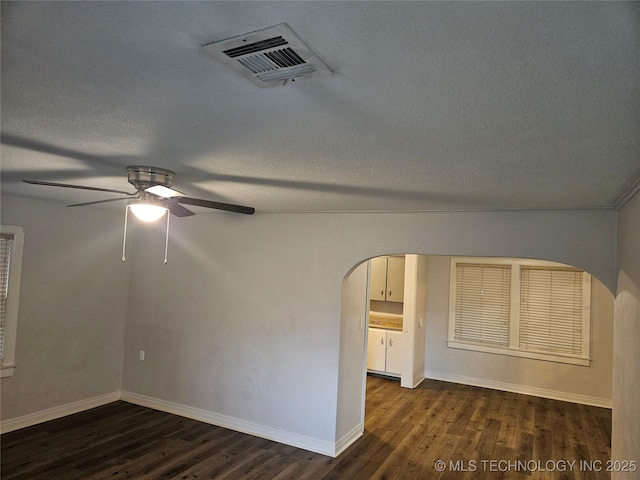 1435 E Oak St, Cushing, OK 74023 - empty room featuring arched walkways, dark wood-style floors, ceiling fan, baseboards, and a textured ceiling
