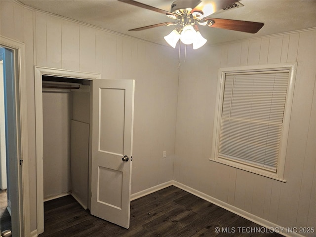 1435 E Oak St, Cushing, OK 74023 - unfurnished bedroom with dark wood finished floors, ceiling fan, baseboards, and wooden walls