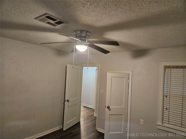 1435 E Oak St, Cushing, OK 74023 - unfurnished bedroom with a textured ceiling, dark wood finished floors, baseboards, and ceiling fan