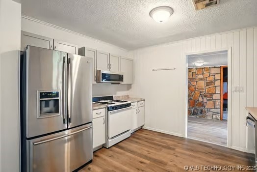 1435 E Oak St, Cushing, OK 74023 - kitchen featuring stainless steel appliances, wood finished floors, a textured ceiling, light countertops, and baseboards